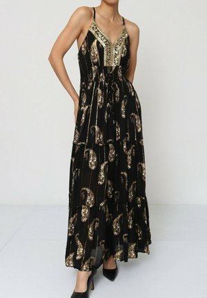 Robe maxi en tissu noir dotée de motifs paisley dorés et d'accents de sequins, avec un décolleté en V et des bretelles spaghetti ajustables.