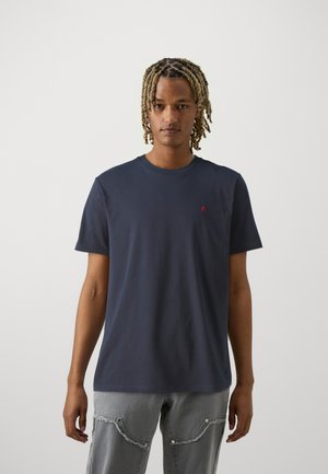T-shirt in cotone navy con maniche corte e scollatura rotonda, caratterizzato da un piccolo logo rosso sul lato sinistro del petto. Tessuto morbido, vestibilità rilassata.