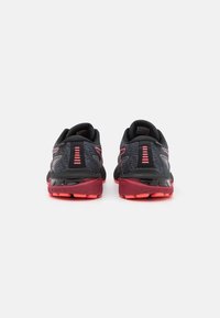 Un par de zapatillas de correr negras y rosas visto desde la parte posterior, destacando el talón con tela estampada y suelas texturizadas.