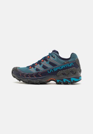 La Sportiva outdoor shoes in blue and gray, featuring a textured upper, orange accents, and a rugged black outsole for traction.