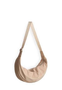 Borsa a tracolla beige realizzata in tessuto morbido, con una forma a mezzaluna, tracolla regolabile e dettaglio con cerniera per una chiusura sicura. Texture liscia.
