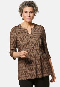 Braun gemusterte Bluse mit V-Ausschnitt, dreiviertel Ärmeln und Knopfdetails. Sie hat ein geometrisches Design und eine lockere Passform.