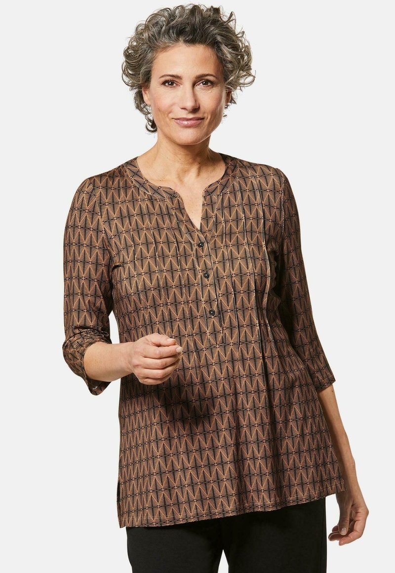 Braun gemusterte Bluse mit V-Ausschnitt, dreiviertel Ärmeln und Knopfdetails. Sie hat ein geometrisches Design und eine lockere Passform.