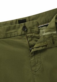 Olive green pants feature a zipper fly, button closure, and side pockets. Made from smooth fabric with visible stitching detail.