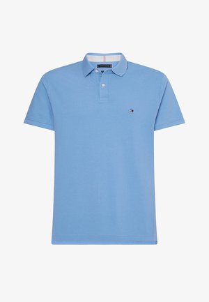 Camisa polo azul claro de algodón con mangas cortas, una tapeta de dos botones y un pequeño logo en el pecho. Textura suave y corte clásico.