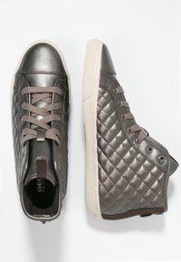 Vysoké tenisky v metalicky šedé barvě s prošívanou texturou, šedými tkaničkami a gumovou podrážkou. Obsahují zesílené očka a poutko na zadní straně.