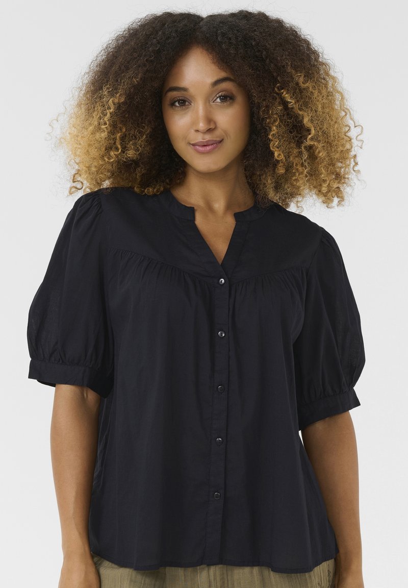 Camicia nera con bottoni e maniche a sbuffo; tessuto leggero e testurizzato; design plissettato e colletto a dosso; vestibilità su misura con morbide drappeggi.