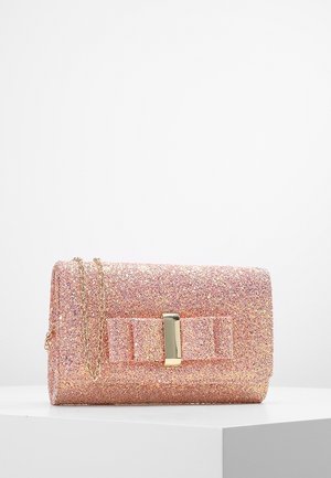 Petit sac à main rectangulaire rose pailleté avec un nœud texturé et une fermeture rectangulaire dorée, reposant sur une surface blanche avec une bandoulière en chaîne.