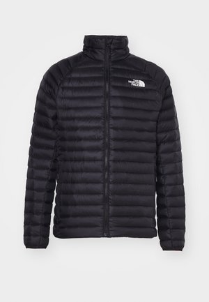 Giacca a vento nera con zip frontale, colletto alto e cuciture orizzontali. Presenta il logo sul petto e polsini elasticizzati. Leggera e isolante.