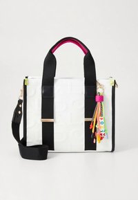 Schwarz-weiße Tragetasche mit Kunstlederakzenten, versehen mit bunten Charme-Details, einem abnehmbaren Schulterriemen und zwei oberen Griffen.