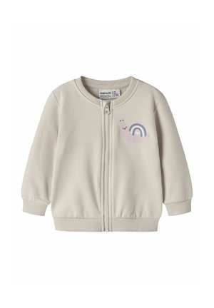 Beżowa kurtka dziecięca z przednim zamkiem błyskawicznym i małą grafiką uśmiechniętego ślimaka z tęczową muszlą na lewej piersi.