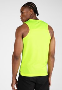 Neon gele sporttanktop met een gestructureerde afwerking en zijsplitten. Heeft een ronde rug en minimale branding op de bovennek.
