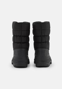 Un par de botas de invierno negras con parte superior de tela acolchada y suela de goma texturizada, mostradas desde la parte trasera sobre un fondo blanco.