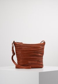 Hnědá kožená crossbody taška s plisovanou strukturou, zipovým uzávěrem a nastavitelným popruhem. Na přední straně se nachází obdélníková značková visačka.