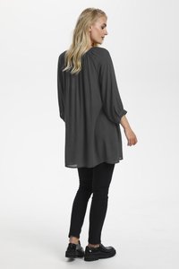 Blouse à manches longues, gris foncé, avec une coupe décontractée, un col rond et un détail plissé au dos, associée à un pantalon noir ajusté et à des chaussures noires.