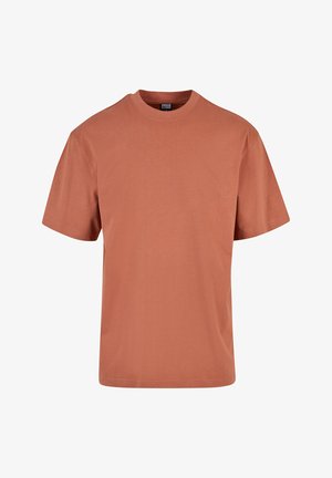 Tricou scurt cu mânecă, de culoare ruginită, realizat dintr-un material moale, cu decolteu rotund și o croială lejeră, cu tiv drept. Nu are modele proeminente.