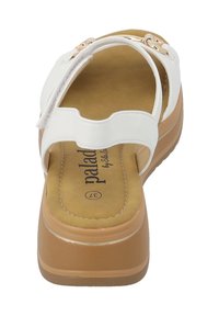 Sandali platform bianchi con una texture liscia, dotati di cinturini regolabili e una soletta imbottita. La suola esterna è marrone chiaro con una leggera lucentezza.