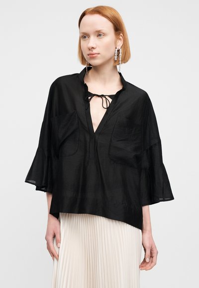 Μαύρη μπλούζα με βαθύ V λαιμόκοψη, λεπτομέρεια με κορδόνι και φαρδιά μανίκια. Διαθέτει δύο μπροστινές τσέπες και είναι κατασκευασμένη από ελαφρύ, υφασμάτινο ύφασμα με υφή.