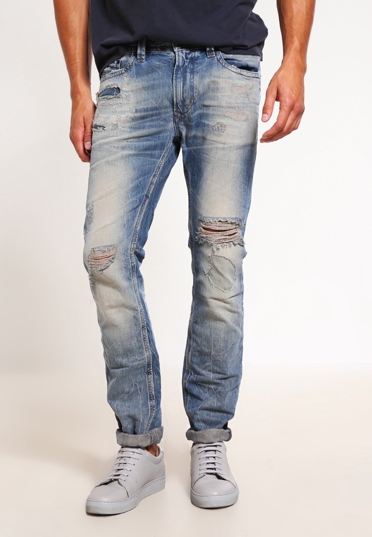 Huvudblå denimjeans med tapered passform, prydda med flera revor och blekta partier, fulländade med en uppvikt fåll och standardfickor.