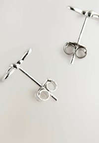 Orecchini a perno in argento con un design circolare e liscio e un retro a forma di T. La superficie è lucida con una finitura riflettente.