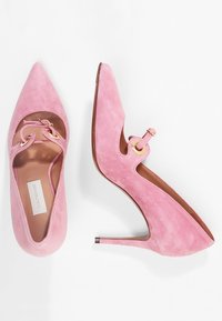 Escarpins en daim rose avec un bout pointu, des côtés découpés et des accents en métal doré. Talon stiletto élancé et doublure intérieure lisse.
