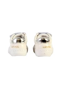 Sneakers bianchi con un accento argentato metallico sul tallone, texture liscia e un sottile dettaglio del logo in oro sul lato.