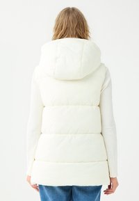 Weißer Puffer-Weste mit großer Kapuze, gestepptem Design und horizontalen Nähten. Hat eine lockere Passform und eine weiche Textur. Rückansicht.