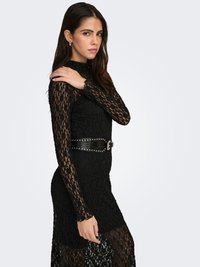 Vestido de encaje negro con mangas largas y cuello alto simulado, con una textura transparente y una silueta ajustada, acentuado por un cinturón negro con tachuelas.