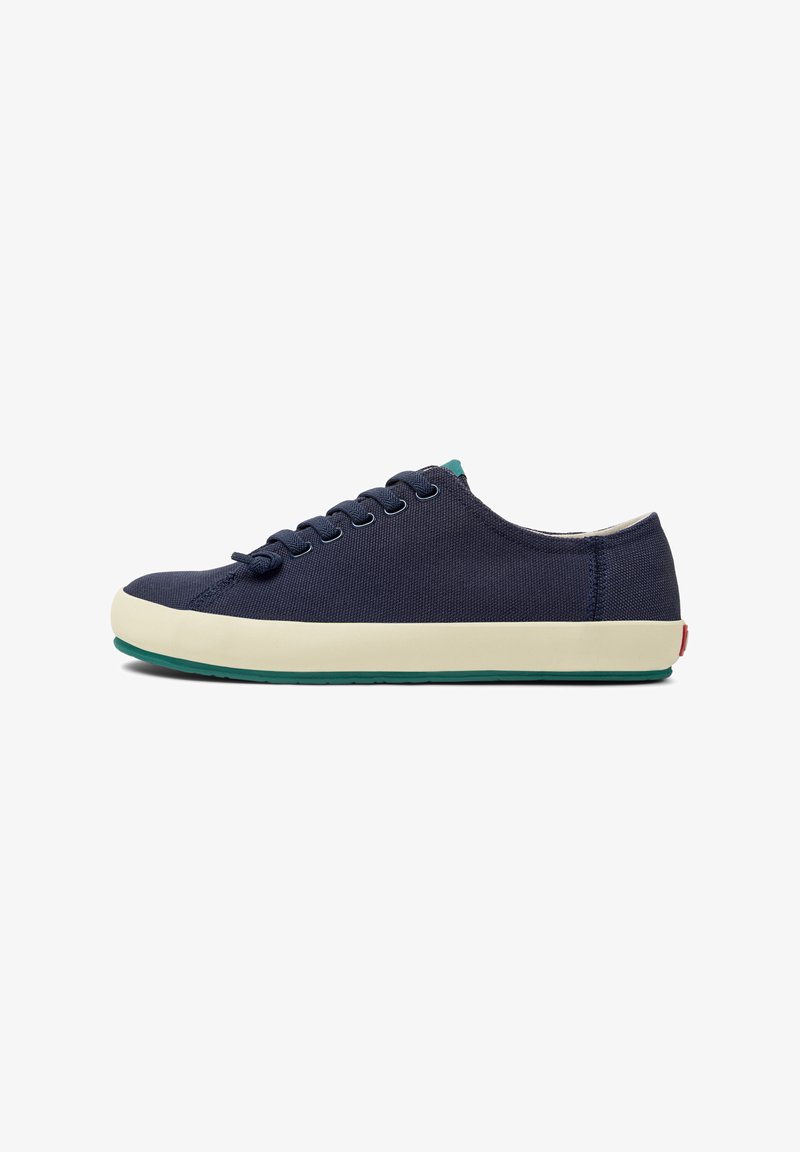 Navy canvas sneakers with a low-profile design, round toe, lace-up front, cream midsole, and a green rubber outsole.