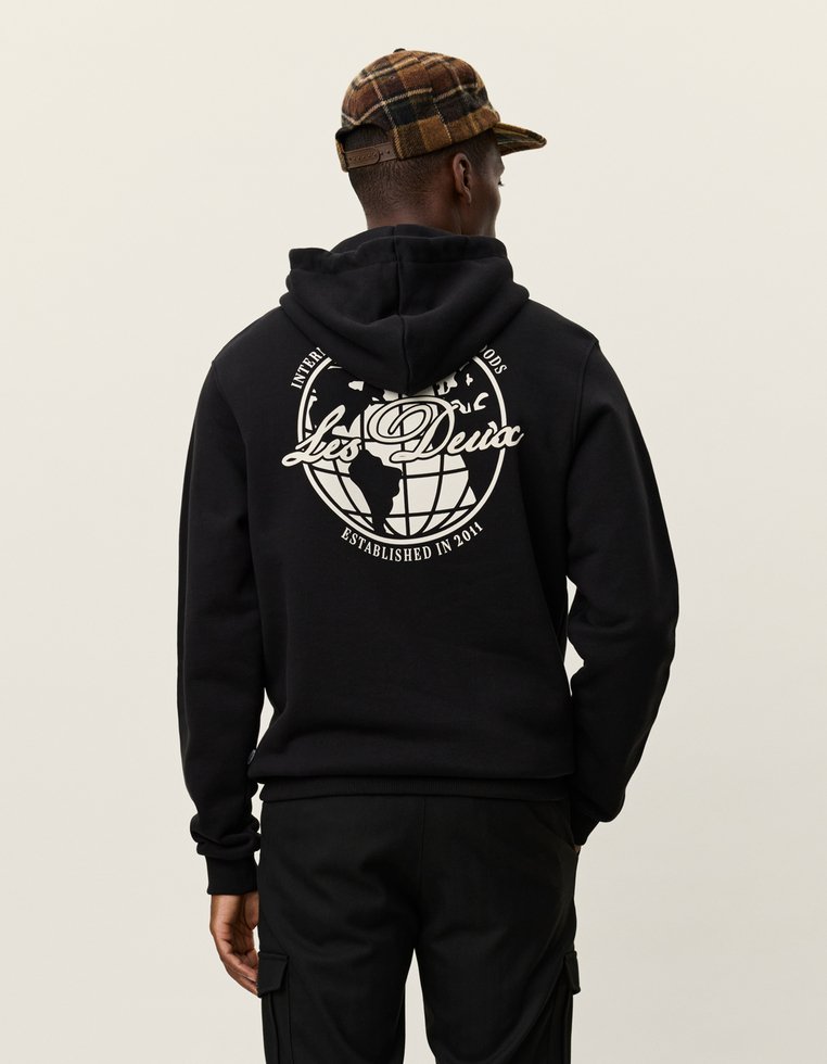 Czarna bluza z kapturem z białą grafiką globu i tekstem z tyłu. Wykonana z miękkiego materiału, ma kieszeń kangurką i sznurek do regulacji kaptura.
