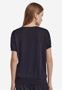 Granatowy top z krótkim rękawem, okrągłym dekoltem, teksturowaną tkaniną i prążkowanym dołem, z podwiniętymi rękawami i luźnym krojem.