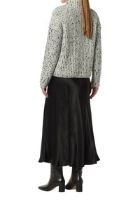 Helles graues, strukturiertes Strickpullover mit einem hohen Kragen, kombiniert mit einem schwarzen Satinrock, der bis zur Mitte der Wade fließt, und schwarzen Absatzstiefeln.