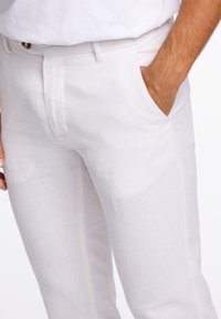 Lehké lněné kalhoty v krémově bílé barvě, s texturovanou látkou, poutky na pásek a bočními kapsami. Jednoduchý design s upraveným střihem.