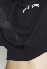 Svart sweatshirt med avslappnad passform, med grå detaljer och en vit logotyp. Mjuk textur med ribbade manschetter och nederkanter.