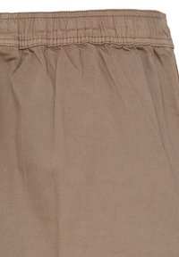 Nahaufnahme von braunen Hosen mit elastischem Bund aus glattem Stoff mit abgesteppten Details.