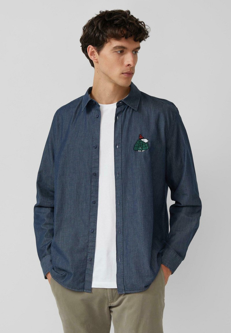 Granatowa jeansowa koszula na guziki z długimi rękawami, z zielono-białym haftowanym wzorem żółwia na lewej piersi.
