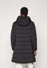 Manteau doudoune noir avec capuche, présentant un design matelassé, une longueur longue et une texture lisse. Aucun matériel visible ni embellissements.