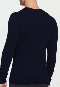 Camicia a maniche lunghe in tessuto blu navy a tinta unita, con scollatura rotonda e design aderente. Tessuto liscio senza motivi o accenti visibili.