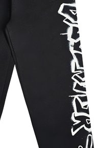 Leggings neri con una stampa bianca in stile graffiti lungo il lato sinistro, caratterizzati da una texture morbida e elastica.
