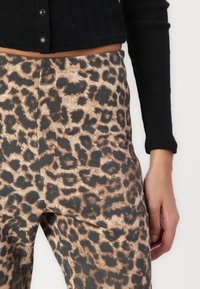 Høydehylser i leopardmønster laget av mykt, teksturert stoff. Fargepaletten inkluderer brune og svarte mønstre, med en tettsittende design.