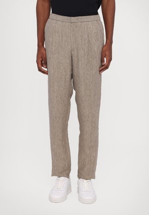 Lysbrune, linned trøjer i blanding med en tekstureret finish, med plisseret front og tapered ben, parret med hvide sneakers.