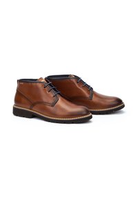 Botas de tobillo de cuero marrón con un acabado suave, puntera redonda y costuras tonales. Presentan un diseño de cordones y suela de goma para mayor tracción.