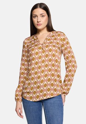 Lange mouwblouse met een v-hals, voorzien van een bloemenpatroon in bruin, oranje en crèmekleurige tinten op een lichte achtergrond.