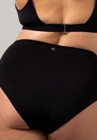 Svart highwaisted bikiniunderdel i mjukt material, med metallogotyp och platta sömmar för komfort.