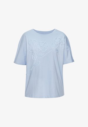 Chemise bleu clair à manches courtes avec col rond et motif floral blanc brodé sur la poitrine et les épaules.