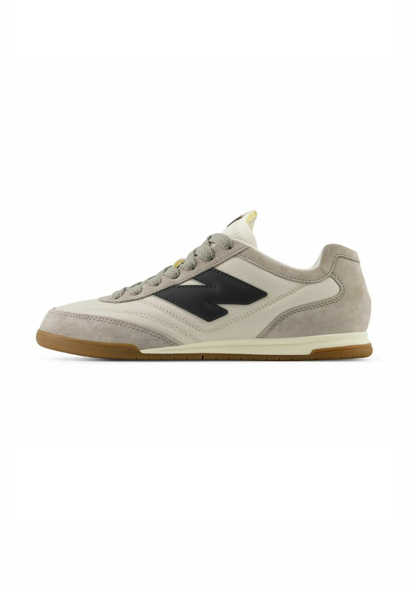 Beige Wildleder- und Mesh-Sneaker mit schwarzem Logo, grauen Schnürsenkeln und Gummi-Sohle. Verfügt über einen gepolsterten Kragen und verstärkte Zehen.