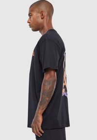 Black cotton t-shirt featuring a graphic design in orange and purple on the back, short sleeves, and a relaxed fit.