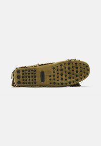 Olivengrøn ruskinds moccasin med frynser, flad brun sål med flere sorte gummipunkter for greb og traction.