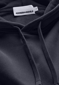 Dunkelblauer Kapuzenpullover mit weicher Textur. Verfügt über eine Kapuze mit Kordelzug, gerippte Bündchen und ein "ARMEDANGELS"-Etikett am Nackenbereich.