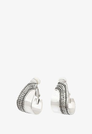 Boucles d'oreilles créoles clipsées ton argent avec motifs noirs texturés à points et lignes sur la surface extérieure, bords arrondis et bandes intérieures lisses.